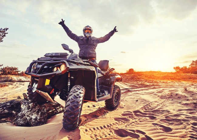 Man on ATV with hands raised in the air